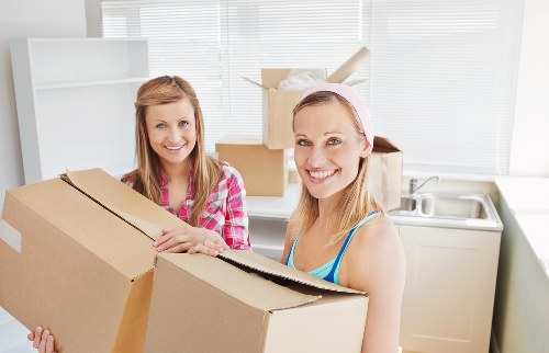 Professional movers carrying furniture down stairs in a West Hampstead flat